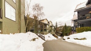 Un sendero cubierto de nieve entre edificios, con cielo despejado.