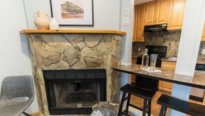 Una cocina con chimenea de piedra, armarios de madera y una barra con taburetes.