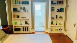 A bedroom with a large bed, a white rug, and built-in shelving with books and decorative items. - Historic home, Heated Mini Pool, near downtown San Antonio! Walk to Zoo & Witte! (San Antonio)