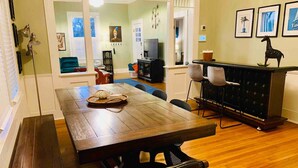 A dining area with a wooden table, benches, and chairs. There is a kitchen area with a black cabinet and a refrigerator. - Historic home, Heated Mini Pool, near downtown San Antonio! Walk to Zoo & Witte! (San Antonio)