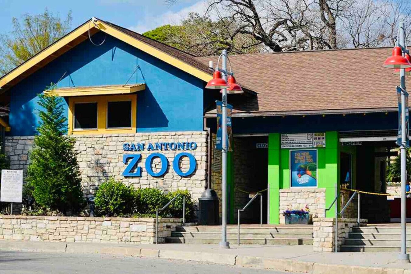 Um edifício com uma placa indicando 'SAN ANTONIO ZOO' e uma entrada verde.