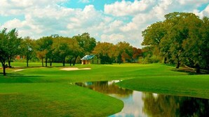 A golf course with a pond, trees, and a building in the background. - Historic home, Heated Mini Pool, near downtown San Antonio! Walk to Zoo & Witte! (San Antonio)