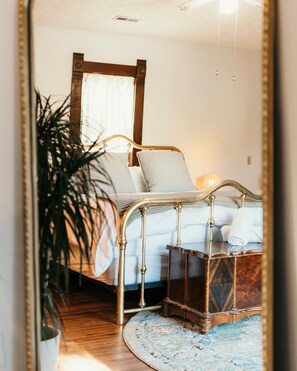 Ein Schlafzimmer mit Bett, Nachttisch und Spiegel, der den Raum wiederspiegelt.