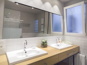 Une salle de bain moderne avec deux lavabos, un grand miroir et une fenêtre.