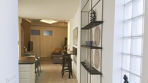 Eine moderne Küche mit Essbereich, ausgestattet mit einem schwarzen Metallregal mit Dekoration und einer grünen Skulptur.