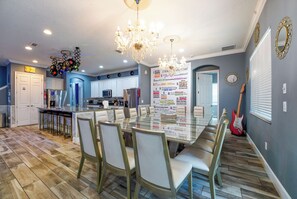 A modern kitchen with a dining area, a chandelier, and a guitar.