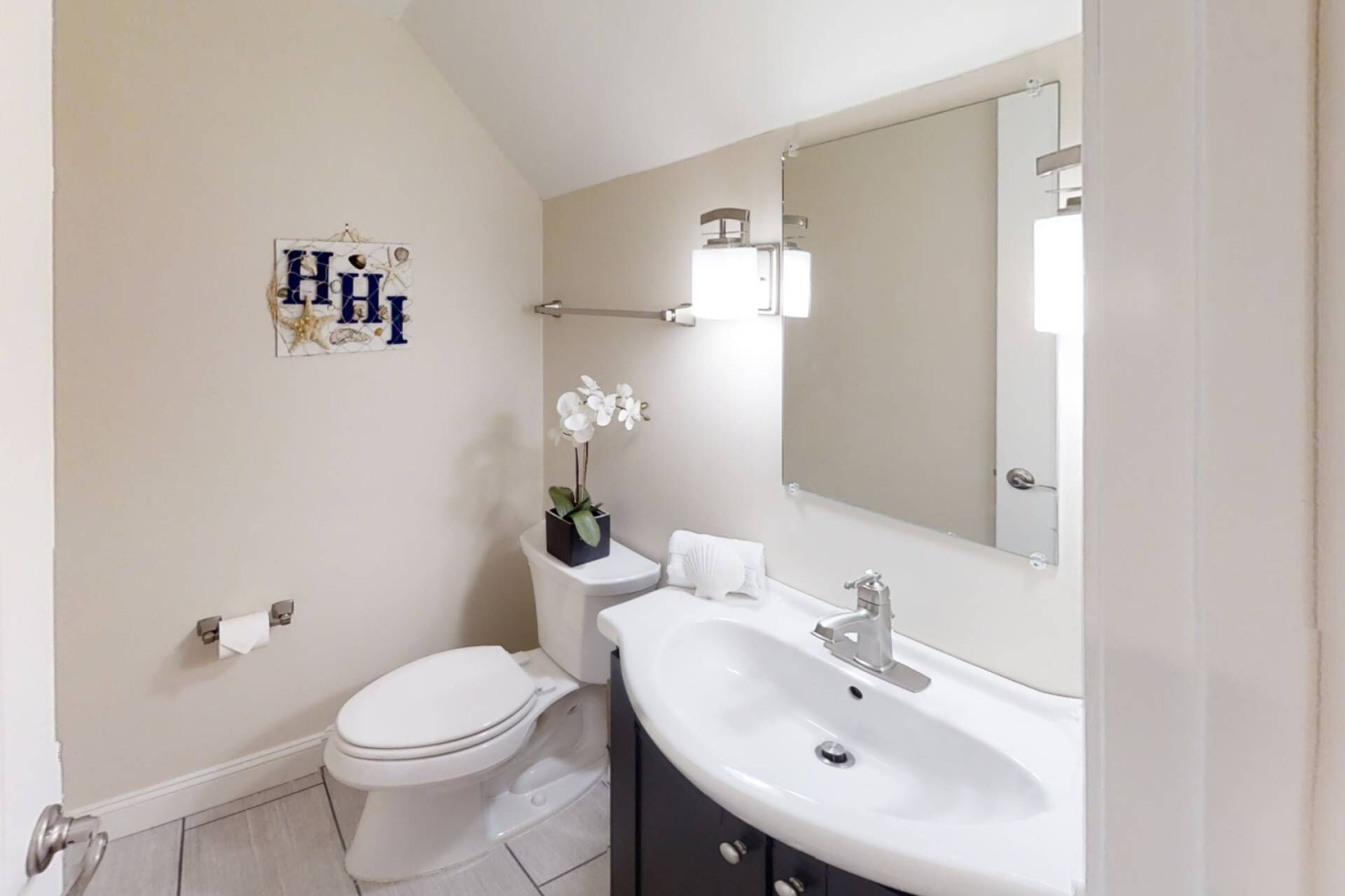 A bathroom with a toilet, sink, and mirror.