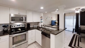 A modern kitchen with stainless steel appliances, white cabinetry, and a central island with a sink and dishwasher.