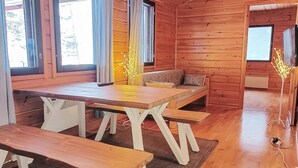 Une cabane en bois avec une table à manger, des bancs et un canapé.