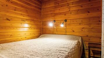Ein Einzelbett in einem Zimmer mit Holzwänden und zwei Wandleuchten.