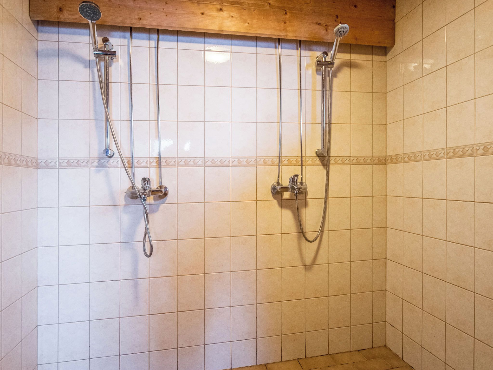 Un espace douche doté de plusieurs pommes de douche et d’un plafond en bois.