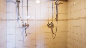 Un espace douche doté de plusieurs pommes de douche et d’un plafond en bois.