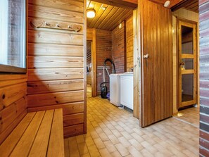 A wooden interior with a bench, a door leading to a bathroom, and a visible washing machine. - Lahdeke by Interhome (Leppävirta)