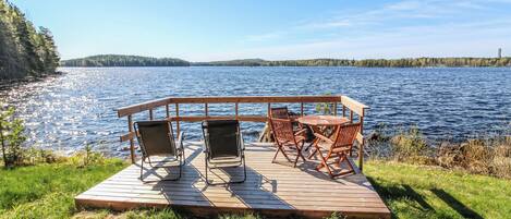 A wooden deck with a table and chairs overlooking a lake.