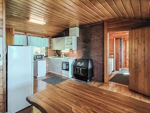 A kitchen with wooden cabinets, a microwave, a stove, and a built-in grill. - Lahdeke by Interhome (Leppävirta)