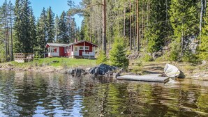 Une cabane au bord d’un lac, avec un quai et un petit bateau.