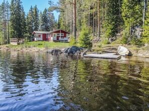 Mökki järven rannalla, jossa on laituri ja pieni vene.