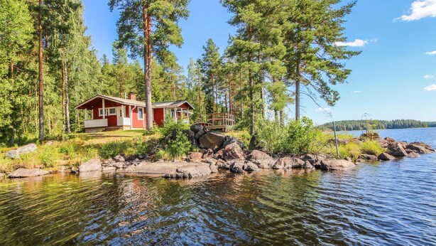 A cabin by a lake surrounded by trees.