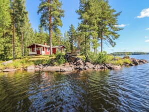 Une cabane avec un quai, entourée d’une forêt et d’un lac.