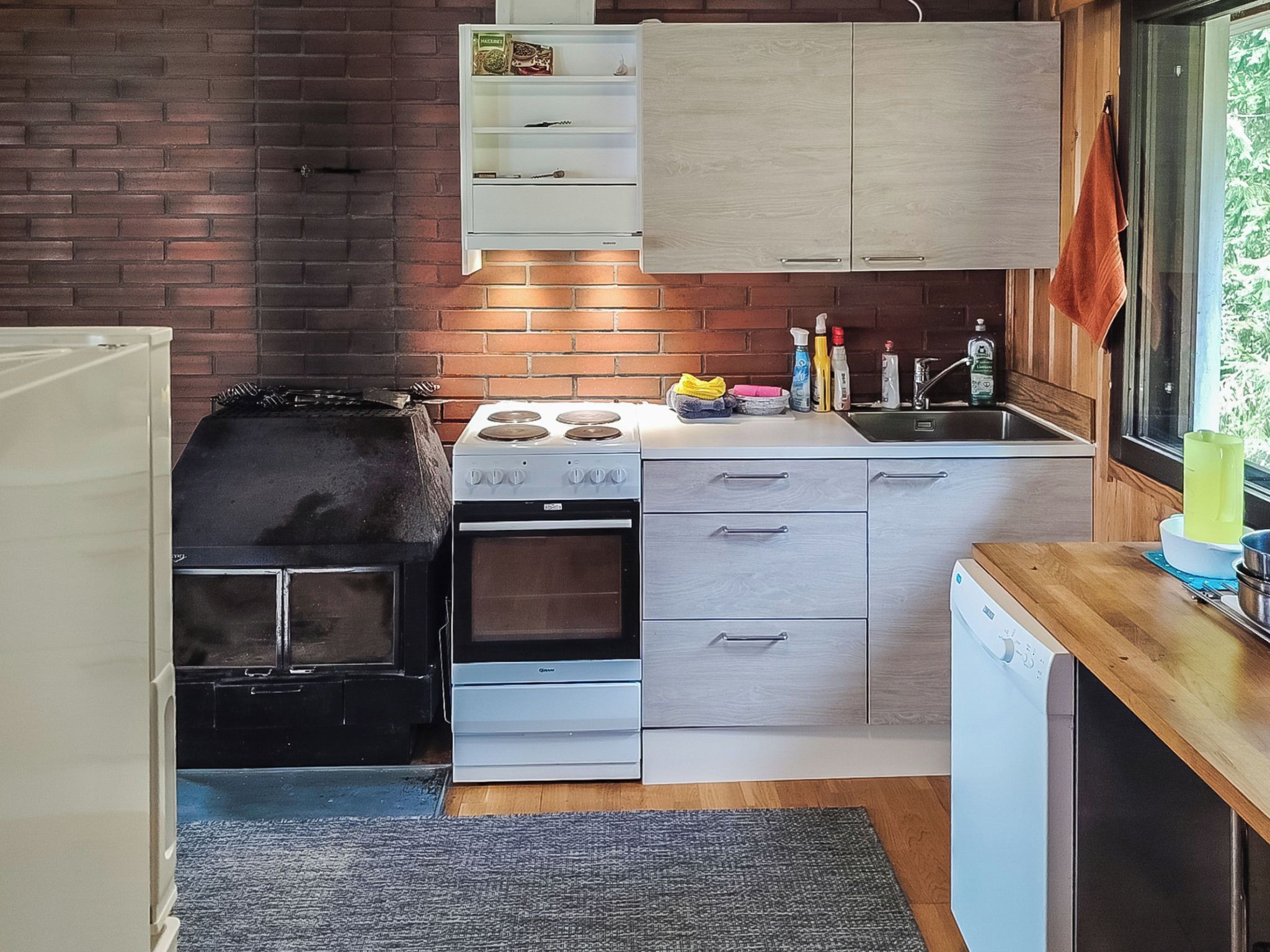 Een kleine keuken met een gasfornuis, oven en een vaatwasser.