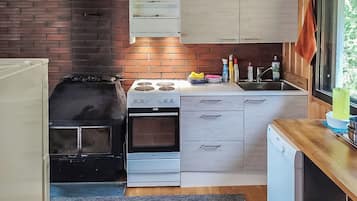 Een kleine keuken met een gasfornuis, oven en een vaatwasser.
