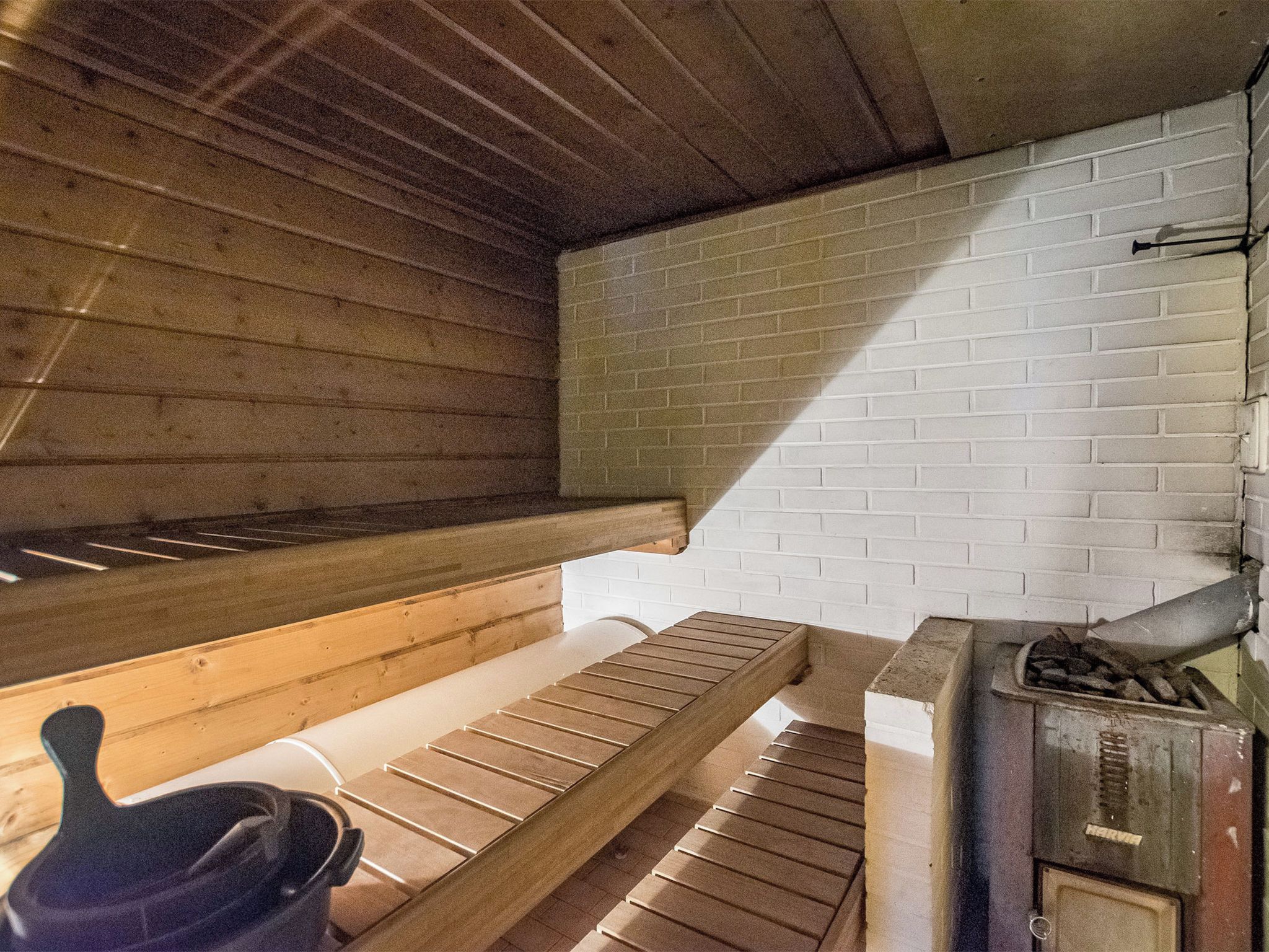 Sauna, jossa on puiset lauteet ja tiiliseinä.