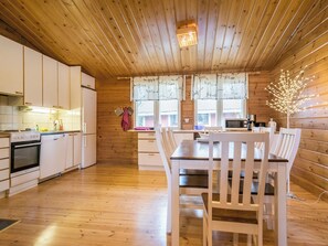 L’intérieur d’un chalet en bois comprend une cuisine, un coin repas et une grande fenêtre.