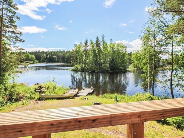 A wooden deck overlooking a calm lake surrounded by dense forest.