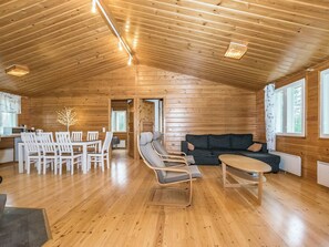 A spacious wooden interior with a dining area, seating, and a view through a doorway.