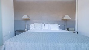 Una habitación de hotel moderna con una cama grande, dos mesitas de noche y una lámpara de techo.