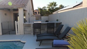 Un espace aménagé au bord de la piscine, comprenant un bar, des sièges et une petite piscine.