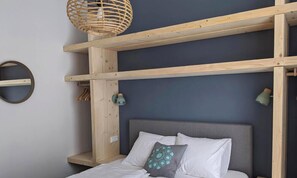 A room with a bed, a headboard, a wooden shelf, a woven light fixture, and a circular wall decoration. - Nieuw Molenwijk, cozy holiday home  4-5 pers.
( Friday to Friday ) (Oostkapelle)