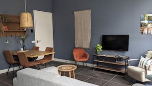 Un soggiorno moderno con zona pranzo, televisione e libreria.