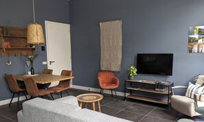 Un salon moderne comprenant un coin repas, un téléviseur et une bibliothèque.