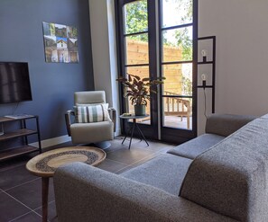A living room with a sofa, armchair, and a television on a stand. - Nieuw Molenwijk, cozy holiday home  4-5 pers.
( Friday to Friday ) (Oostkapelle)