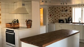 Eine moderne Küche mit weißen Schränken, einer Kochinsel aus Holz, einem Einbauofen und einer strukturierten Spritzschutzwand.
