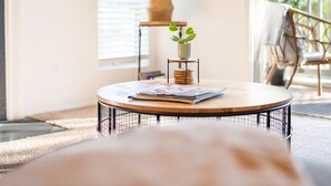 Ein gemütliches Wohnzimmer mit einem runden Couchtisch, einem Kamin und Blick ins Freie.