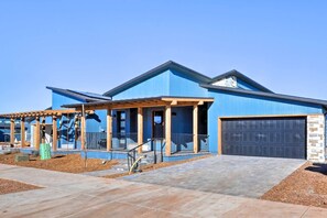 Uma casa moderna de dois andares com fachada azul, varanda coberta e garagem.