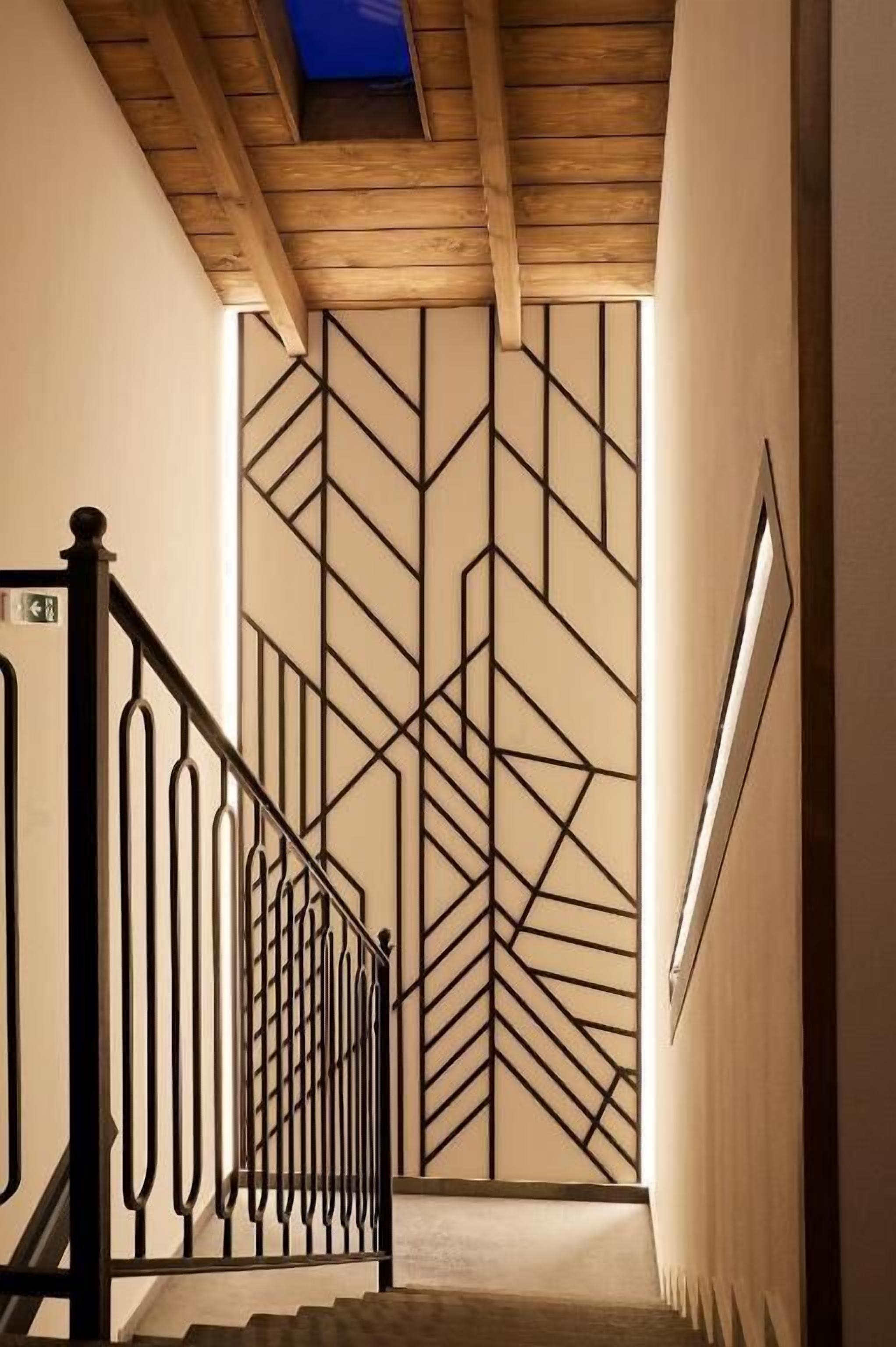 A staircase with a geometric-patterned wall and a wooden ceiling.