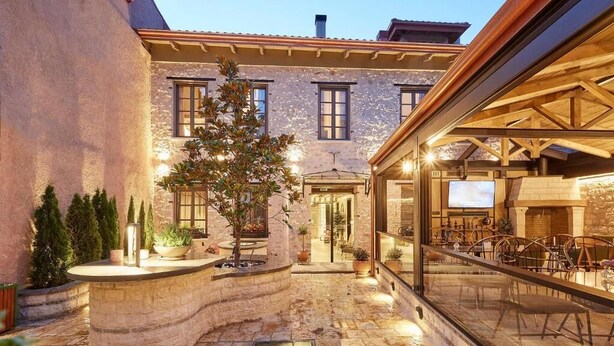 Un patio con una fuente de piedra, plantas en macetas y un área de descanso con sillas.