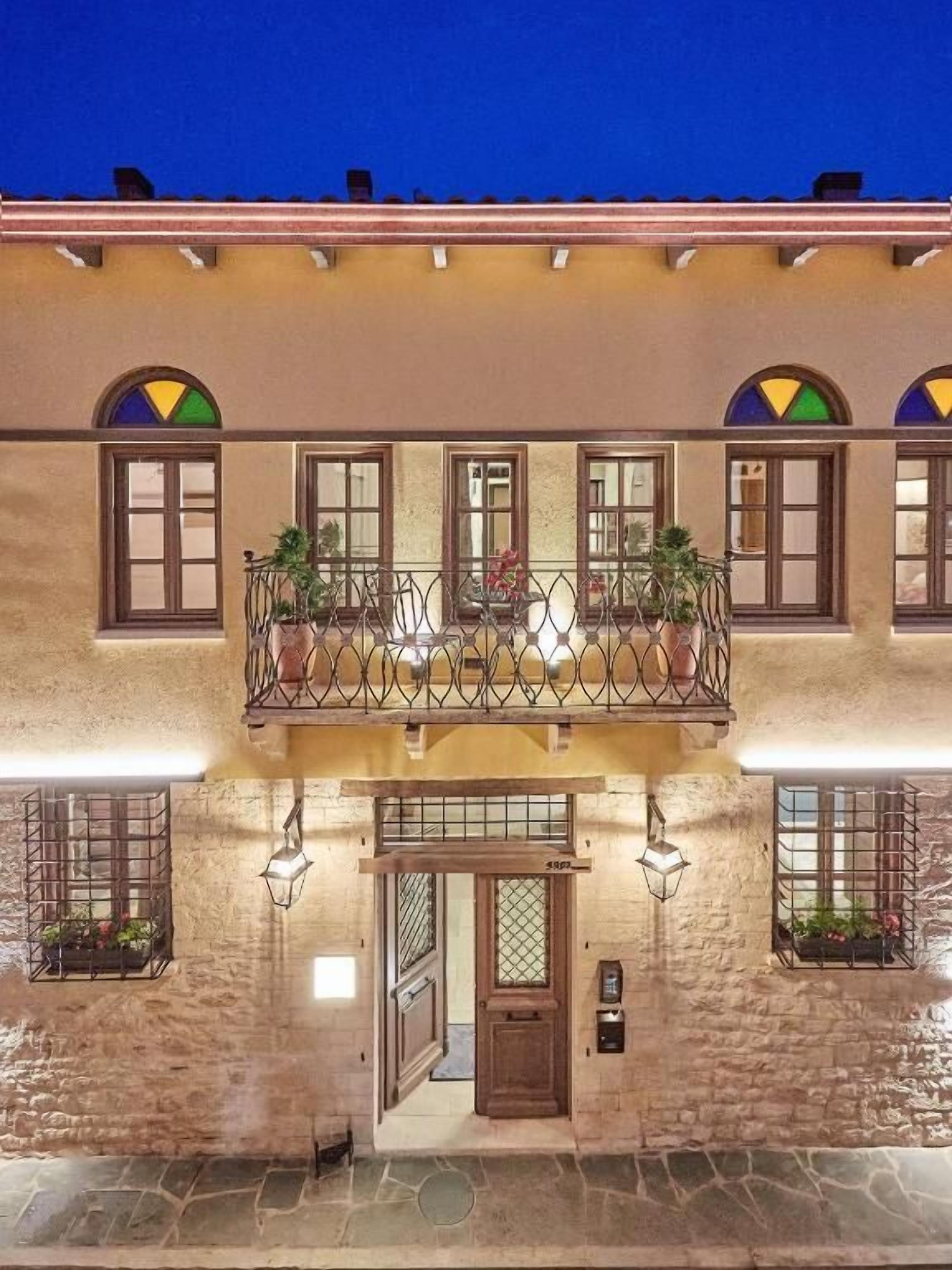 Un edificio di due piani con un balcone, facciata in pietra e numerose finestre.