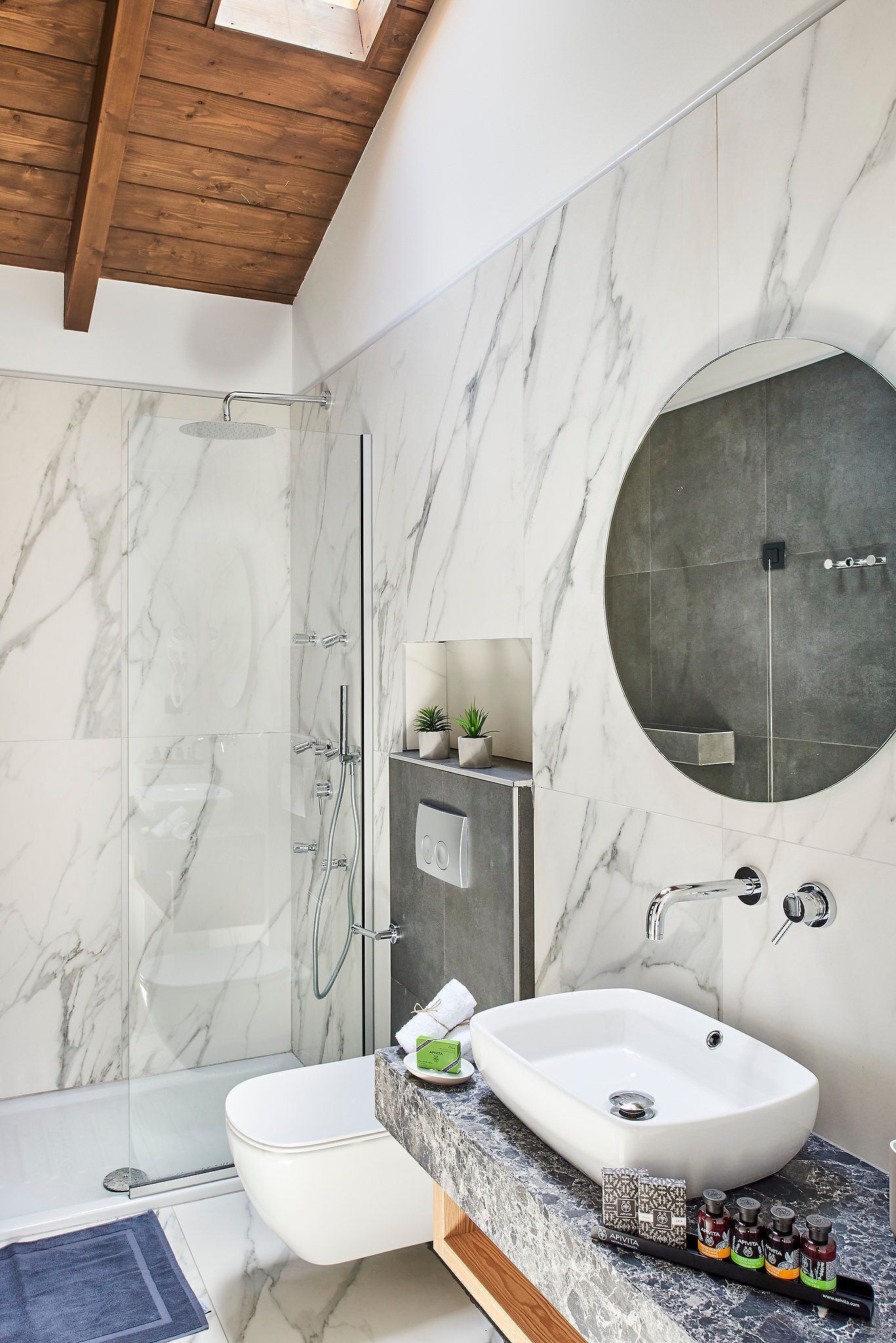 A modern bathroom with a glass-enclosed shower, a white sink, and a large mirror.