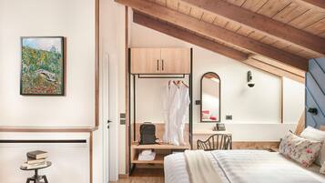 A bedroom with a bed, a wooden ceiling, a painting, a wardrobe, a mirror, and a desk with a chair.