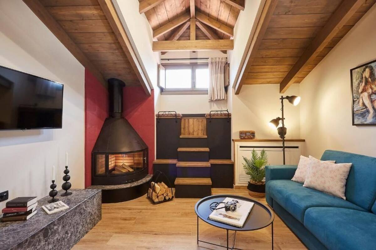 Un salón acogedor con chimenea, un sofá azul y un televisor de pantalla plana.
