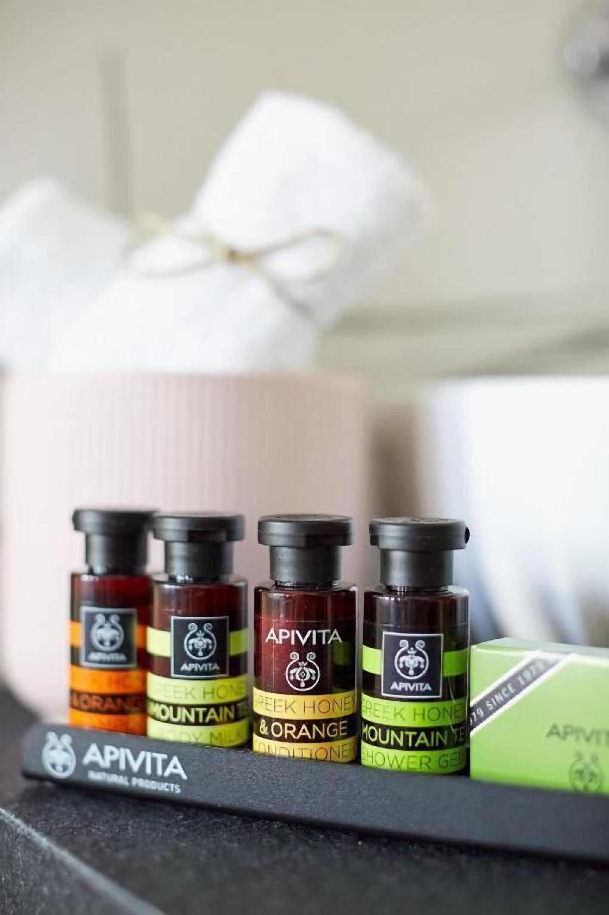 A row of Apivita essential oil bottles on a shelf, with a green box and a white tissue box in the background.