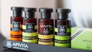 A row of Apivita essential oil bottles on a shelf, with a green box and a white tissue box in the background.