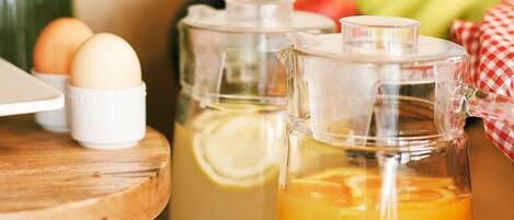 A breakfast setting with a pitcher of orange juice, a glass of orange juice, eggs, and a vase of flowers.