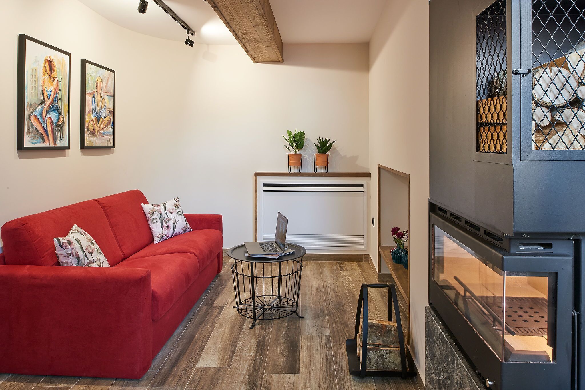 Een moderne woonkamer met een rode bank, een klein rond tafeltje en een open haard.