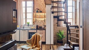 Una cocina compacta con horno empotrado, un comedor con una silla y una escalera que sube a un nivel superior.