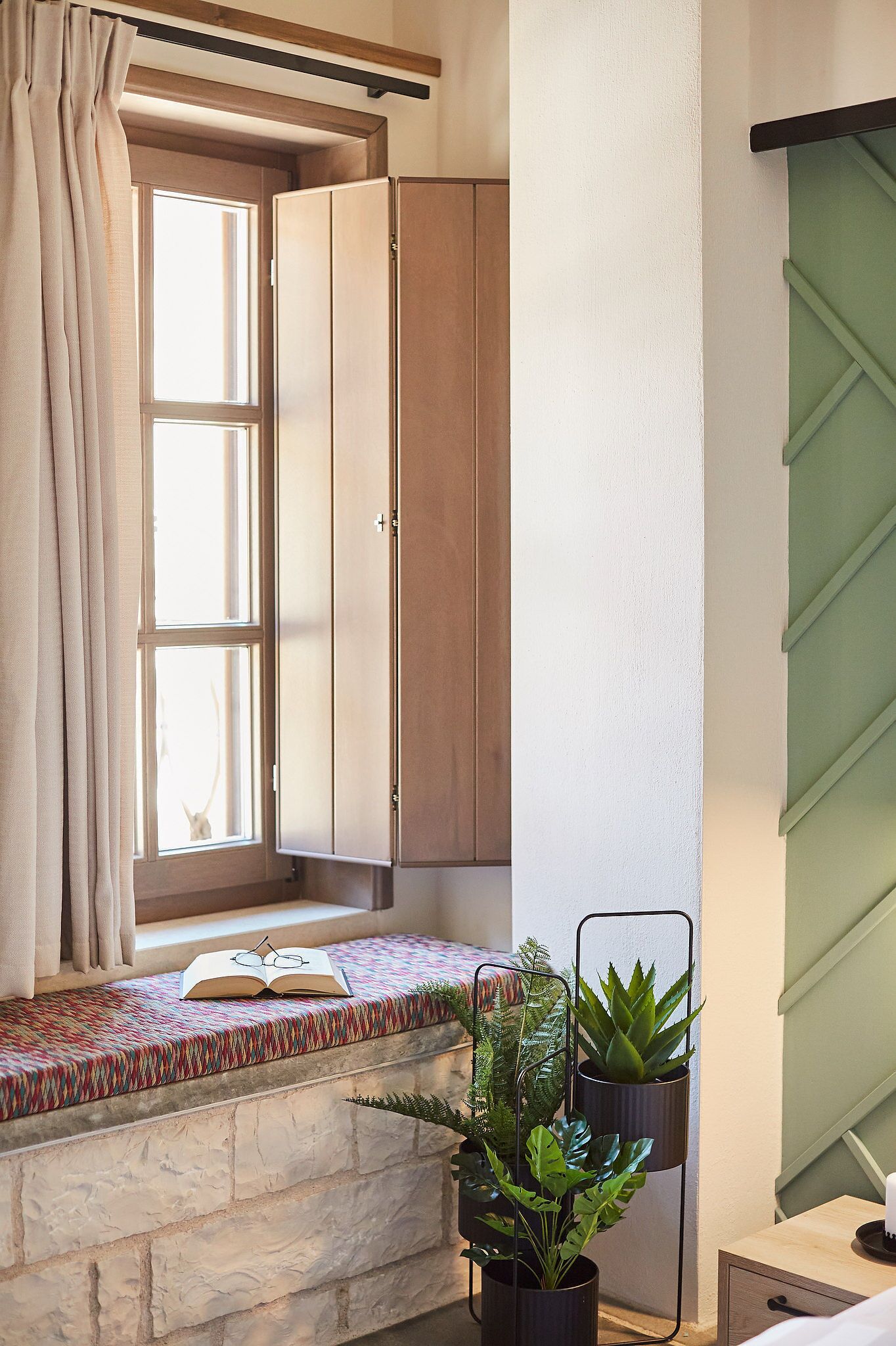 A room with a window, a bookshelf, and a potted plant.